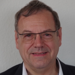 joerg-sievers Porträt eines Mannes mit Brille vor hellem Hintergrund.