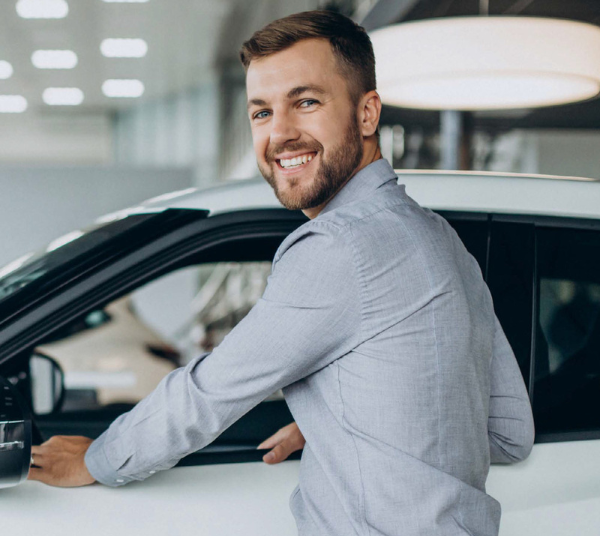 leasing_zugeschnitten Mann steht an einem Auto und legt die Hände auf das heruntergelassene Fenster.