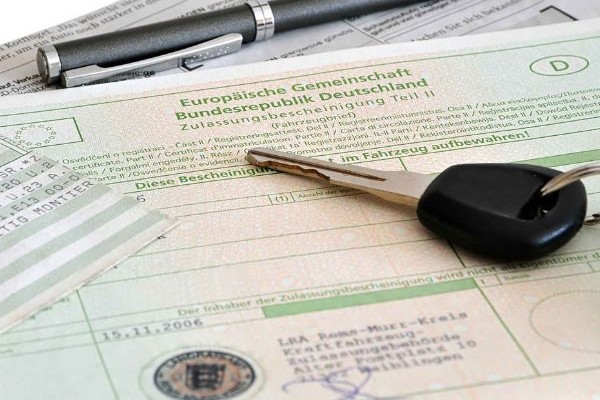Nahaufnahme eines Autoschlüssels auf einem Fahrzeugbrief | Auto online anmelden