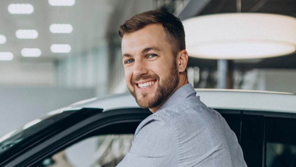Ein Mann öffnet lächelnd eine Autotür | Zulassungsdienst Gewerbe